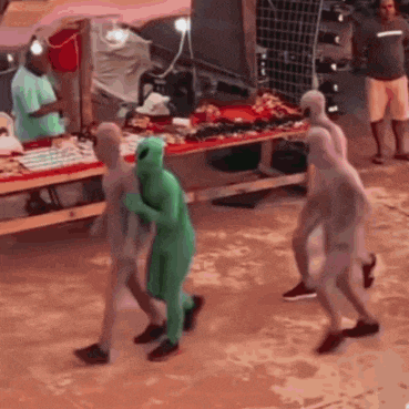a group of people dressed as aliens are walking in a market .