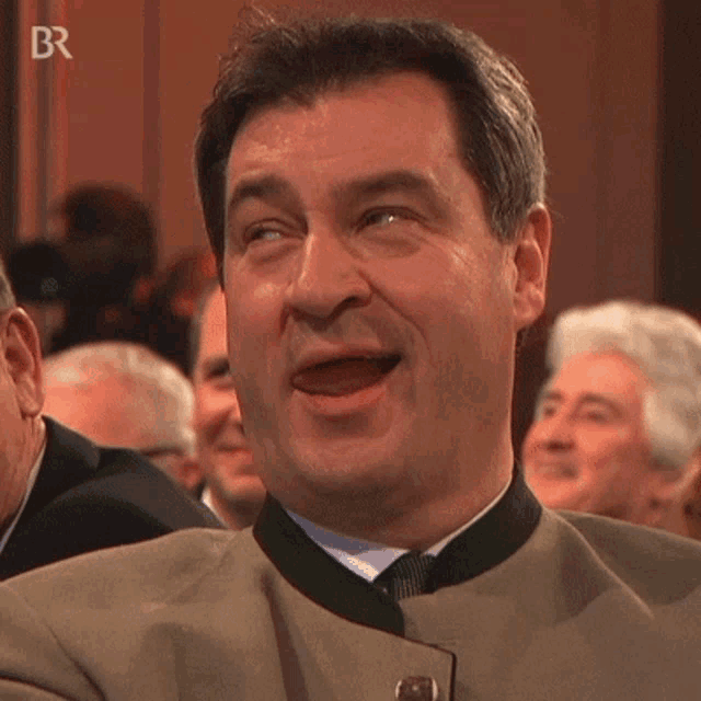 a man is making a funny face in front of a group of people with the letters br on the bottom