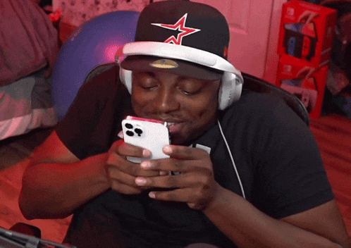 a man wearing headphones and a hat with a star on it is looking at his phone