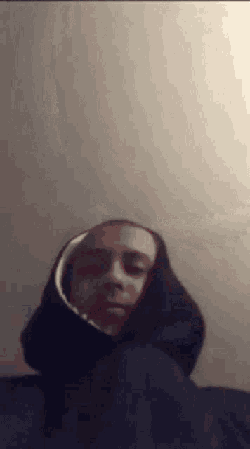 a man is wearing a hoodie and looking at the camera .