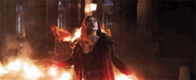 a woman in a red coat is surrounded by flames