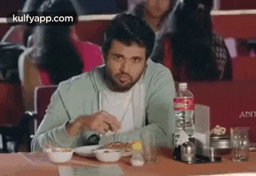 a man is sitting at a table eating a meal .