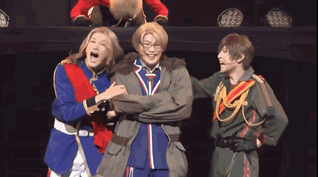 a group of people are standing on a stage and one of them is wearing glasses