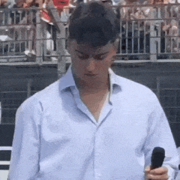a man in a white shirt is holding a microphone in front of a crowd of people .