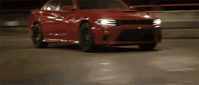 a red dodge charger is driving down a road at night