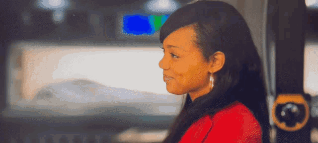a woman in a red shirt is smiling in front of a blue light