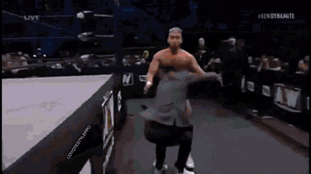 a wrestler is standing in front of a sign that says aew on it