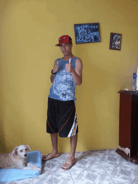 a man giving a thumbs up in a room with a dog