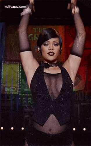 a woman wearing a hat and a sheer top is dancing on a stage .
