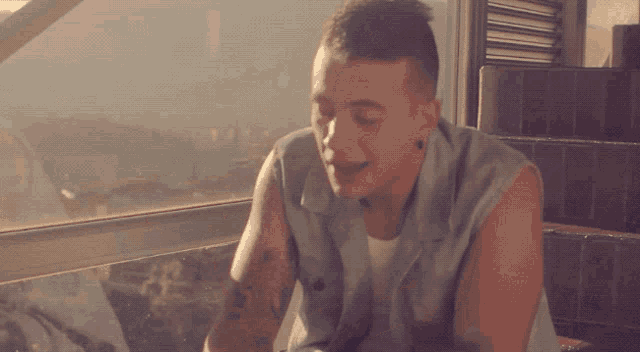 a man with a tattoo on his arm is sitting on stairs looking out a window