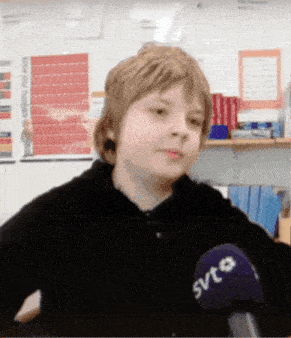 a boy wearing a svt microphone looks at the camera