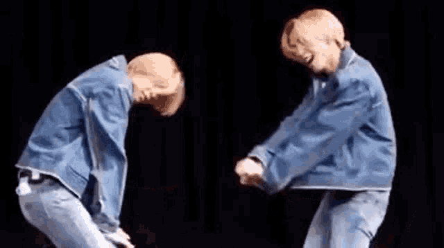 two men in denim jackets are dancing together on a stage .