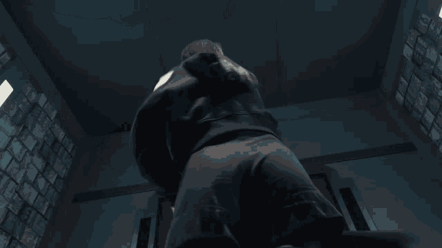 a person is standing in a dark room with a brick wall behind them