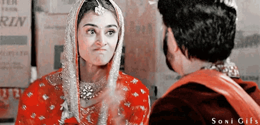 a woman in a red dress looks at a man in a red jacket