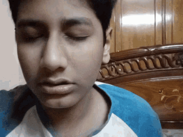 a young man with his eyes closed is wearing a blue shirt