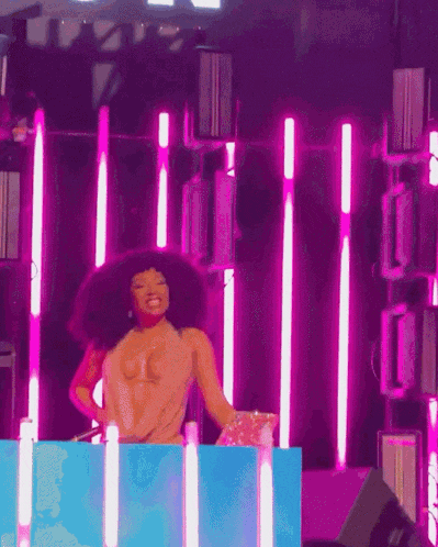 a woman is dancing on a stage with purple lights behind her .
