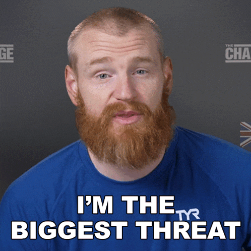 a man with a beard is wearing a blue shirt that says " i 'm the biggest threat "