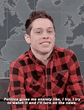 a man wearing a plaid shirt says politics gives me anxiety like