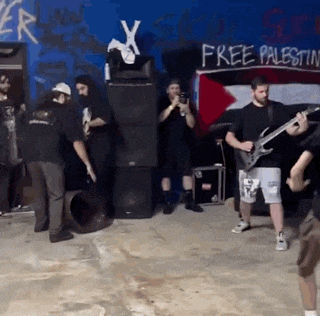 a group of men playing instruments in front of a wall that says free palestine