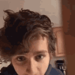 a close up of a person 's face with a messy haircut looking at the camera .