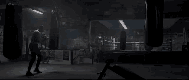 a man is boxing in a boxing ring with punching bags .