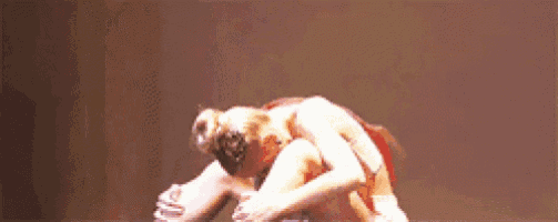 a couple of women are dancing on a stage and one of them is wearing a red dress