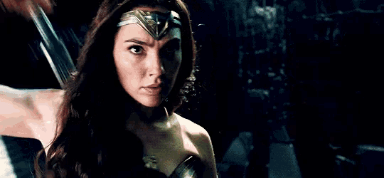 a woman in a wonder woman costume is holding a sword in her hand .