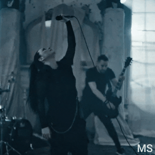 a man playing a guitar next to a woman singing into a microphone with the letters ms on the bottom