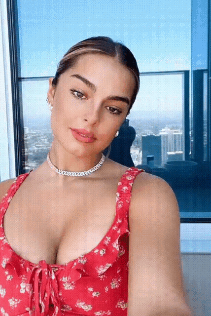 a woman in a red floral dress takes a selfie