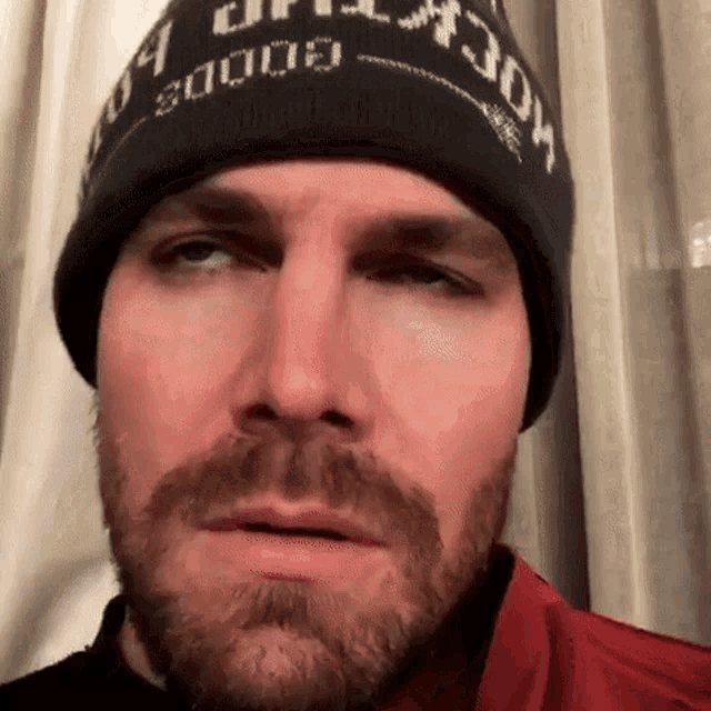 a close up of a man with a beard wearing a beanie .