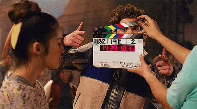 a man holding a clapper board with the number 2 on it in front of his face