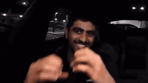 a man in a black shirt is making a heart with his hands .