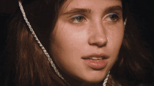 a close up of a woman 's face with a nose ring and blue eyeshadow