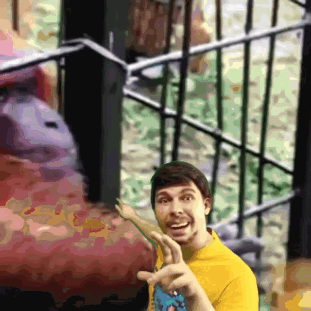 a man in a yellow shirt is standing in front of a fence with a stuffed animal in the background