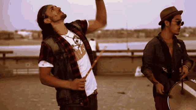 a man in a plaid shirt holds a drum stick