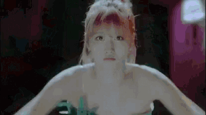 a woman without a shirt is dancing in a dark room with her arms outstretched .