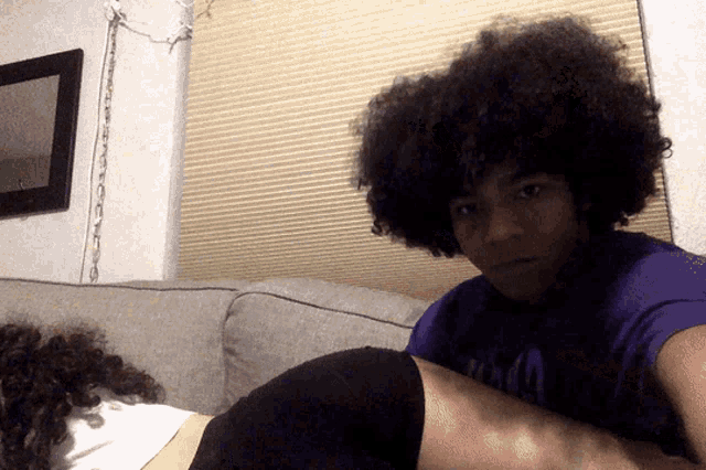 a man with curly hair wearing a purple shirt that says ' miami ' on it