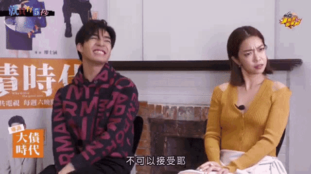 a man and a woman are sitting next to each other with chinese writing on the wall