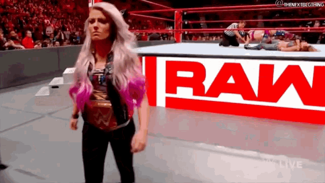 a woman is standing in a wrestling ring in front of a sign that says raw .