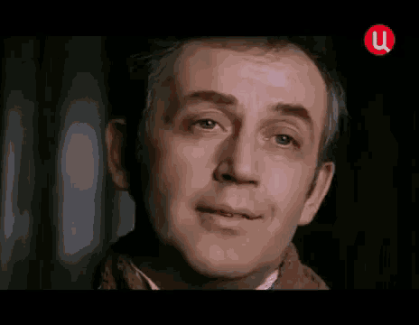 a close up of a man 's face with a red u on the bottom right corner