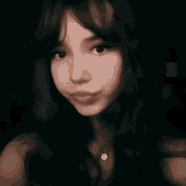 a woman with long dark hair is taking a selfie in the dark