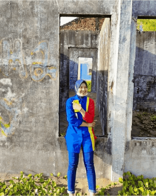 a woman in a blue red and yellow outfit is standing in front of a concrete wall