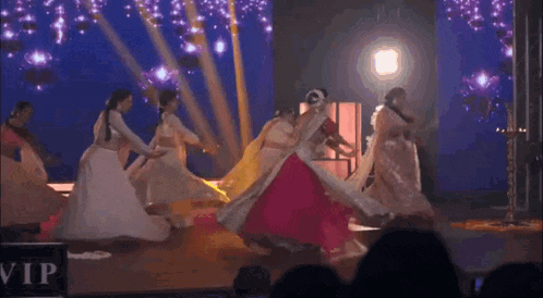 a group of women are dancing on a stage with a sign that says vip in the background .