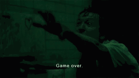 a man is pointing at something in a dark room with the words `` game over '' written on the screen .
