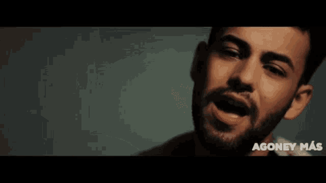 a close up of a man 's face with a beard and the words agoney mac on the bottom .