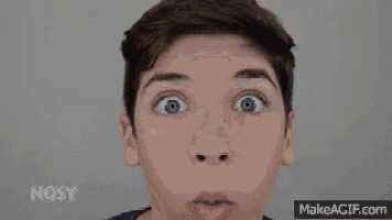 a young boy with braces on his teeth is making a funny face with his hands in the air .