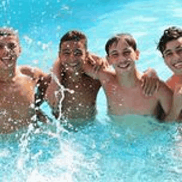 a group of young men are posing for a picture in a pool .