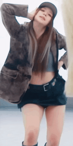 a woman wearing a hat and shorts is standing with her hands on her head .