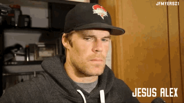 a man wearing a hat and a hoodie with the name jesus alex on the bottom
