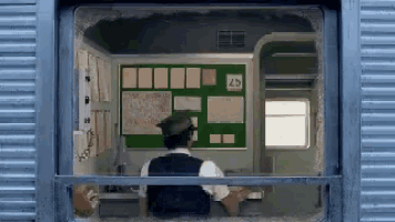 a man is sitting at a counter in front of a green board with the number 25 on it .